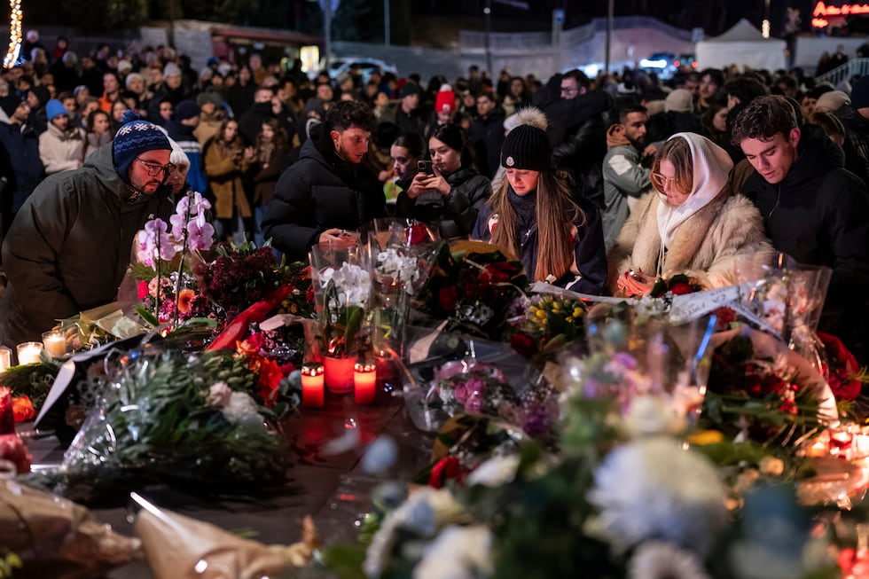 People lay flowers and light candles for the victims of the fire at the "Le Constellation" bar...